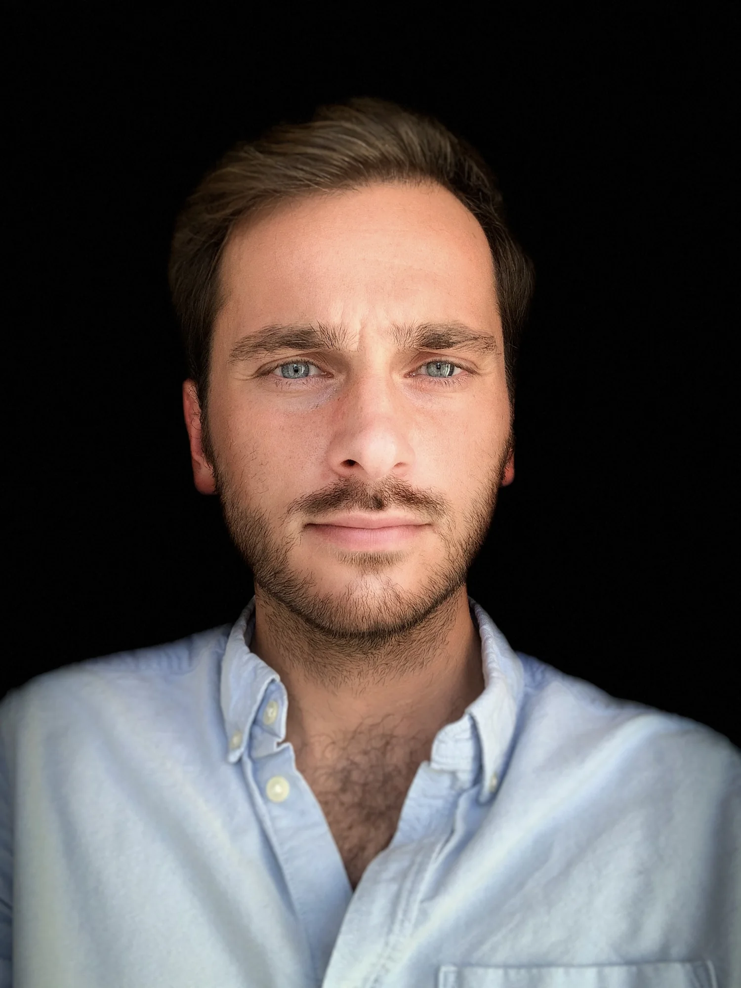 João Montenegro, head and shoulders, in a light blue shirt against a black background