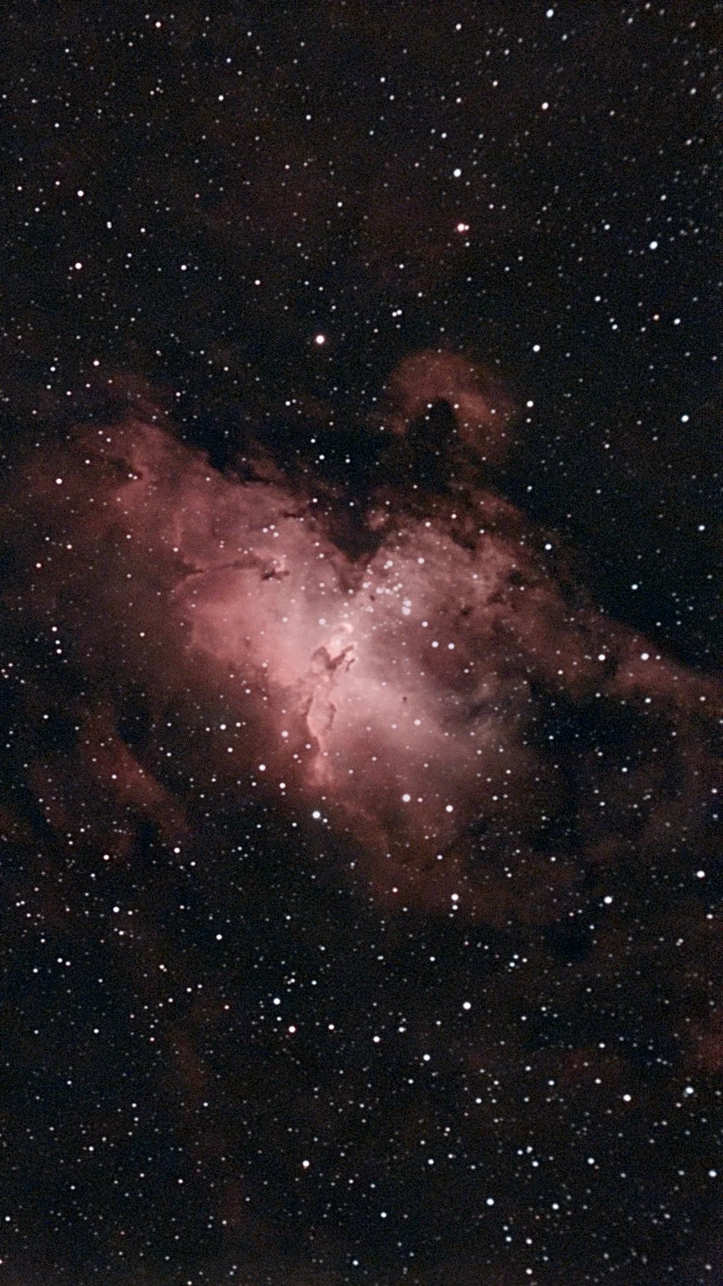 The Eagle Nebula: glowing red gas and dark pillars at the centre of a dense star field