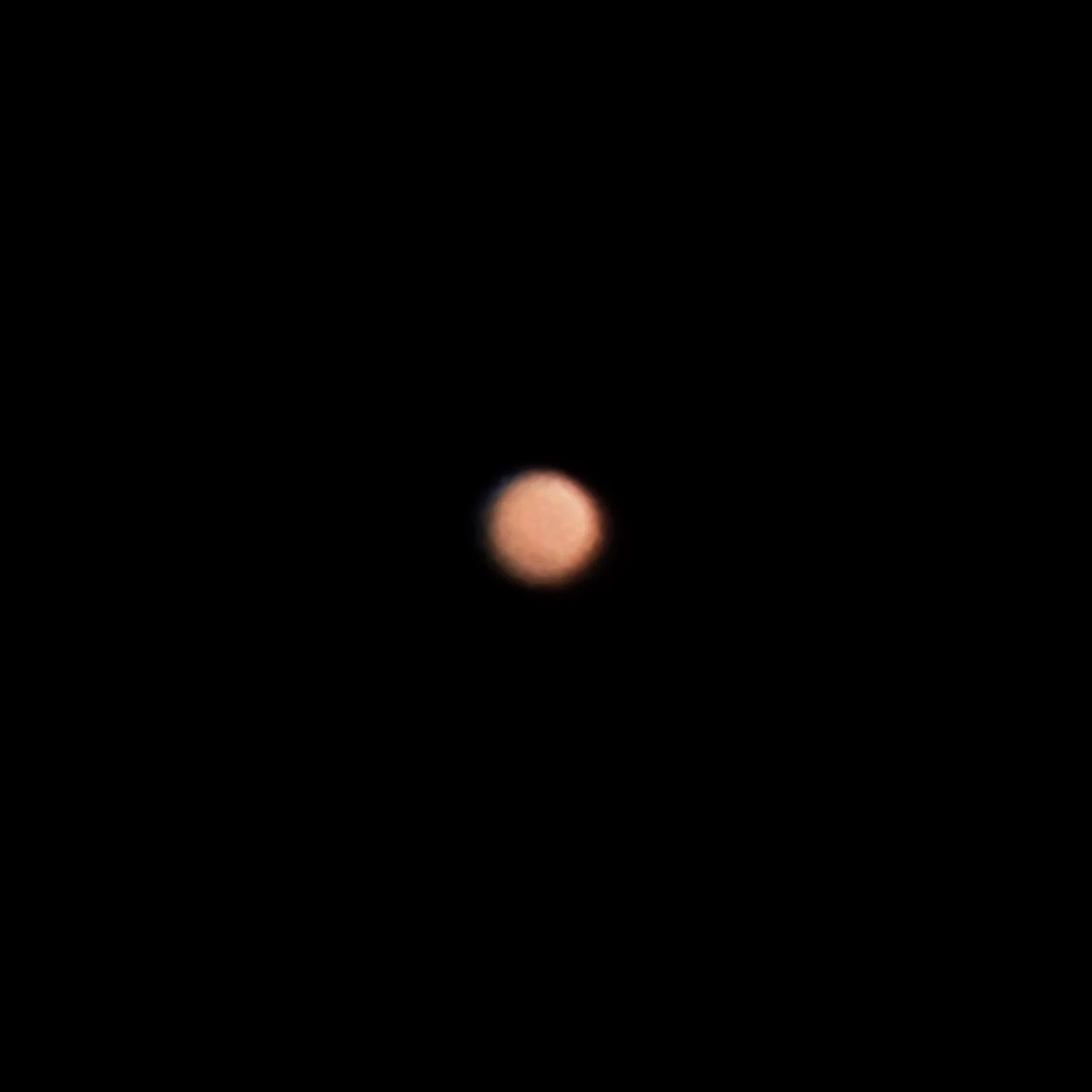 Mars as a small, soft orange disc against black