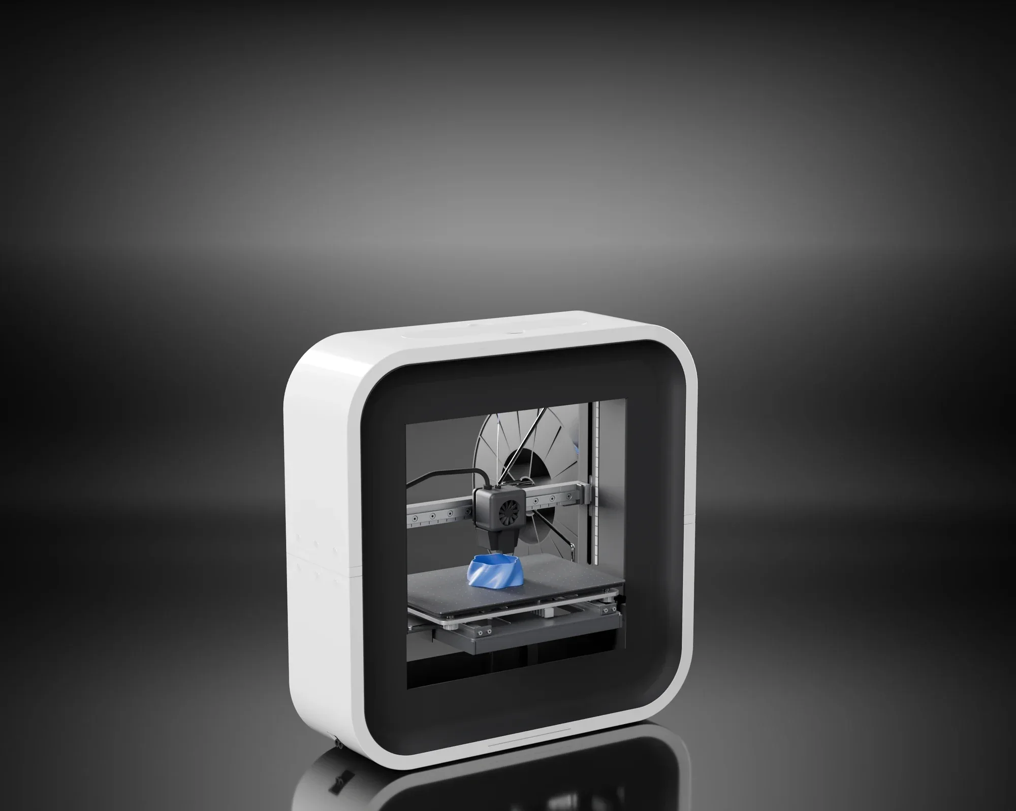 BEETHEFIRST desktop 3D printer: a white ring with a black recess around a window, printing a blue part, on a dark studio floor