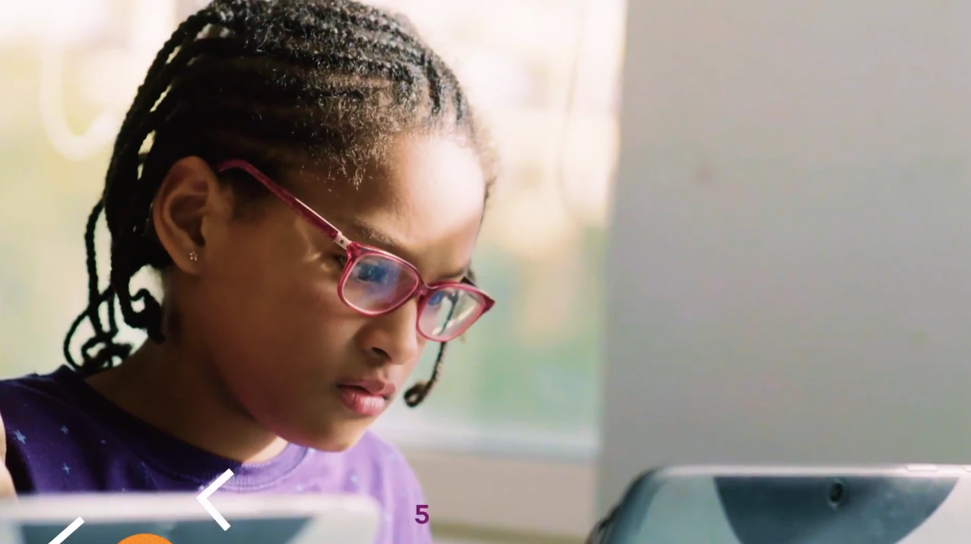 A girl in pink glasses concentrating on a screen
