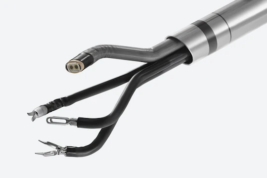 The tip of a single-port surgical probe: three thin black instrument arms with small grippers and a camera head splaying out of a steel tube