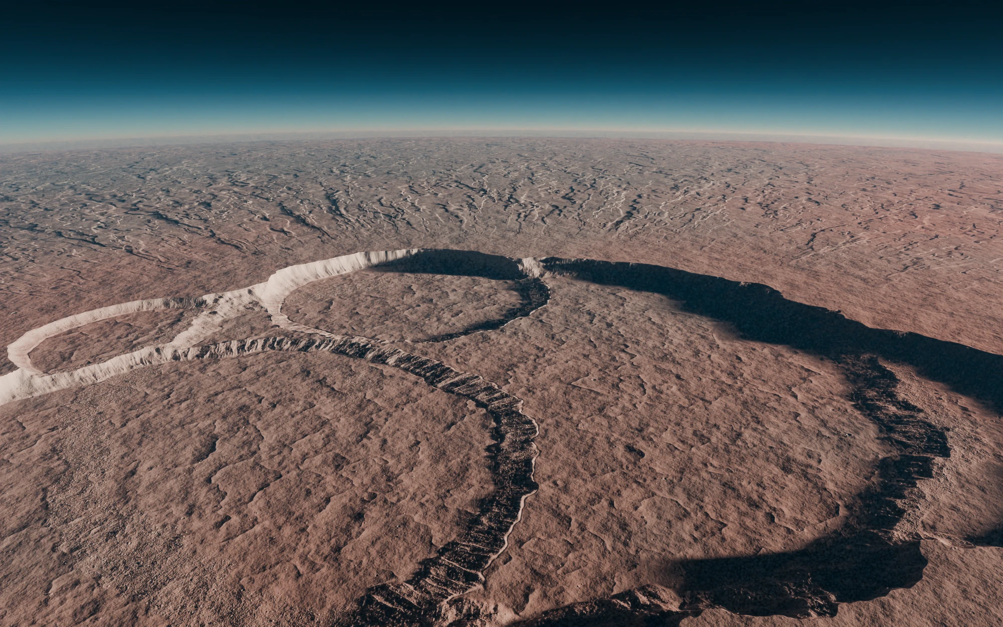 Low sunlight across a reddish volcanic plain, with a chain of round pits at the summit, their walls lit on one side and throwing long shadows, under a thin blue band of air at the horizon