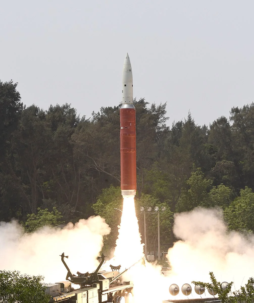 An interceptor with an orange body lifting off from a launcher among trees, smoke spreading on both sides