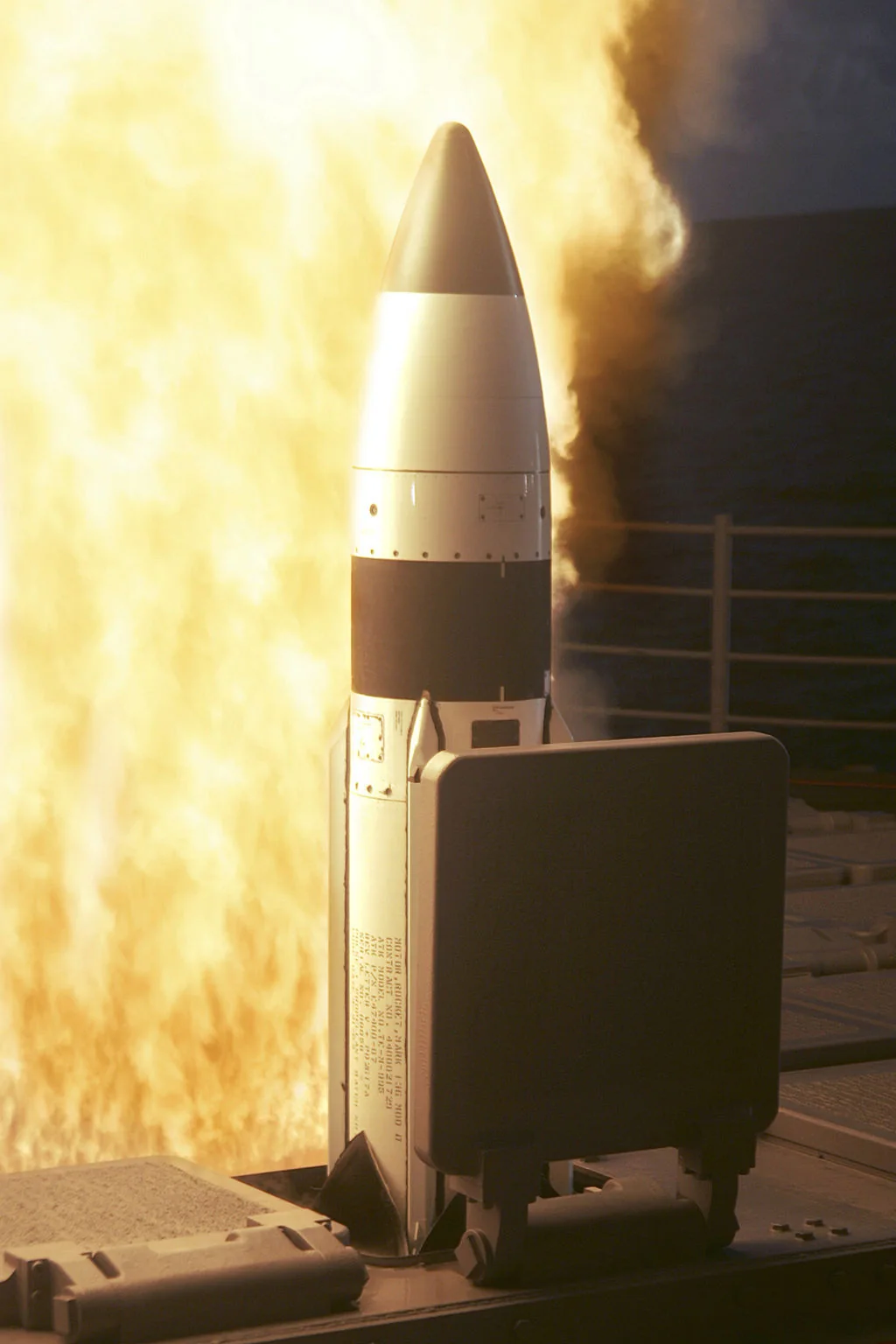 A white missile leaving a ship's deck launcher in a burst of yellow flame