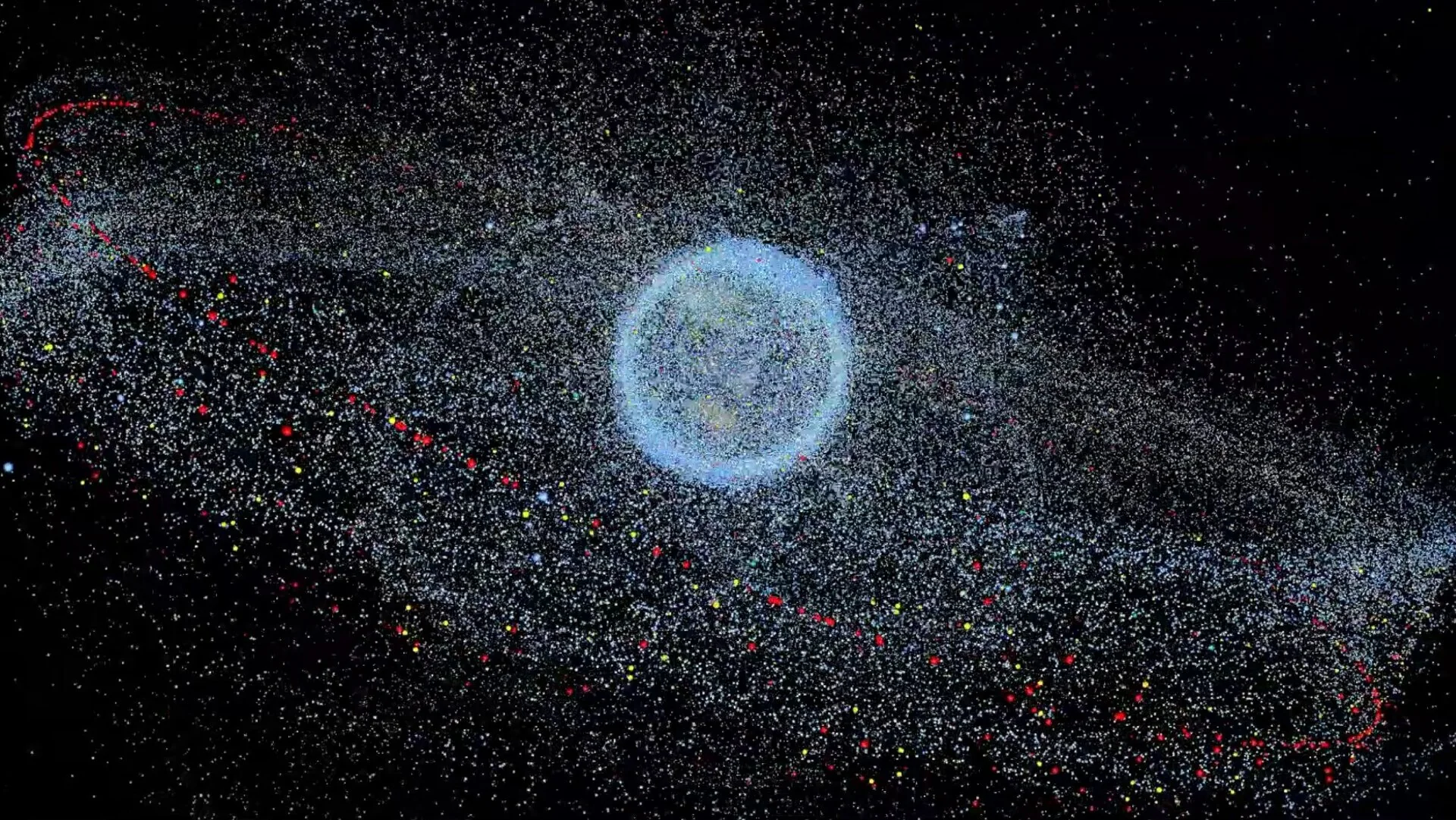 The Earth inside a dense cloud of dots for tracked debris, thickest close to the planet, with a looser ring farther out